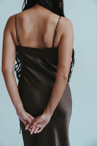 Woman wearing a black slip dress against a plain background