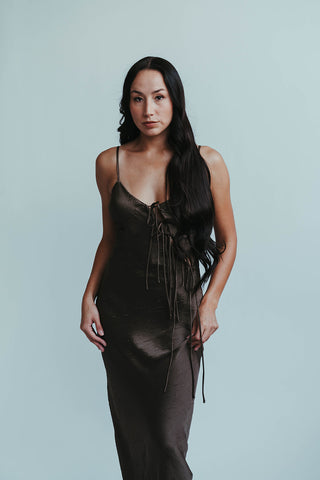 Woman wearing a dark brown dress against a light gray background