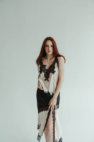 Woman wearing a black and white lace dress against a plain background