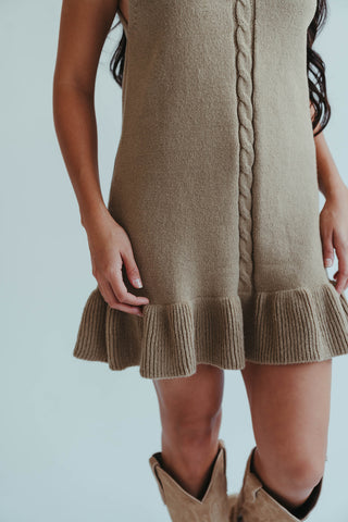 Brown knit dress with ruffled hem and matching boots on a plain background