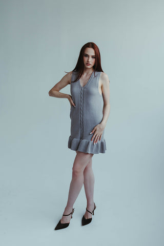 Woman wearing a gray dress against a plain background