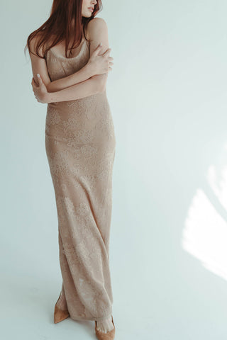 Woman wearing a beige lace dress against a white background