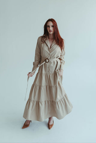 Woman wearing a beige trench coat against a white background