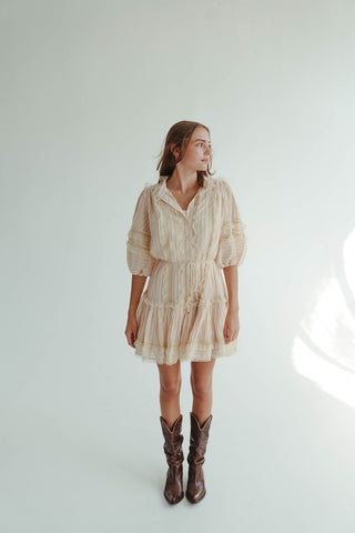 Woman wearing a beige dress and brown cowboy boots on a light background