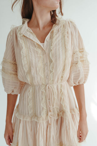 Woman wearing a beige lace dress against a white background