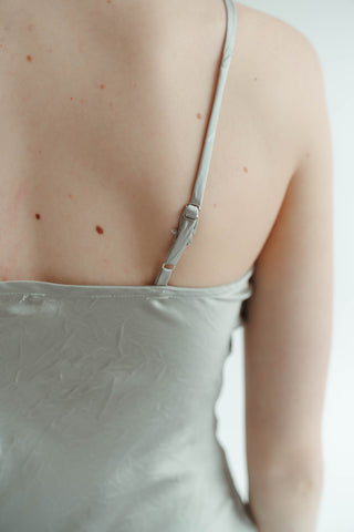 Sage spaghetti strap top worn by a person on a plain background