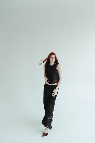 Woman in a black outfit standing against a white background