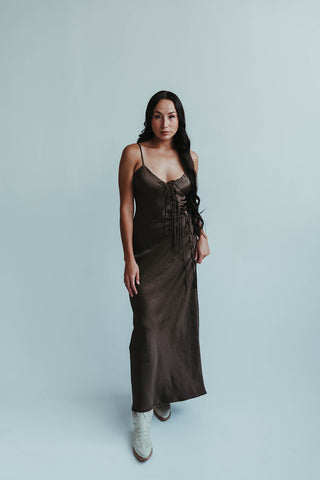 Woman wearing a brown slip dress against a light gray background
