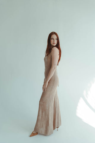 Woman wearing a beige dress standing against a white background