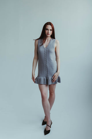Woman wearing a gray dress against a plain background