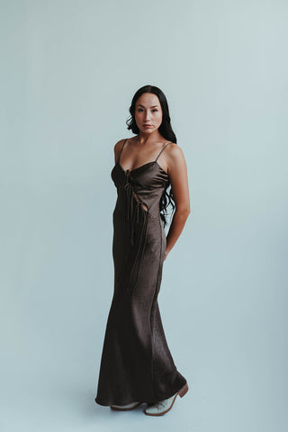 Woman wearing a dark brown evening gown against a light gray background