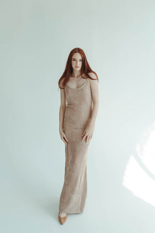 Woman wearing a long beige dress against a white background
