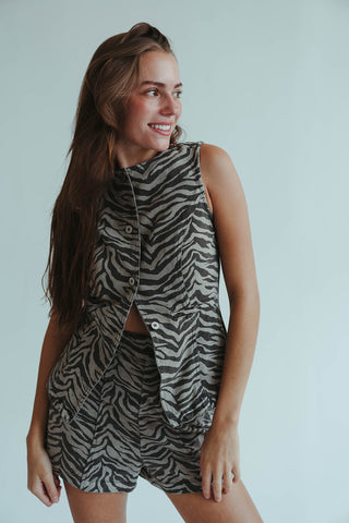 Woman wearing a zebra print sleeveless top and shorts against a plain background