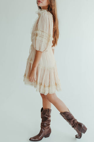 Woman wearing a beige dress and brown boots on a white background