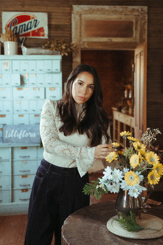 Woman arranging flowers in a rustic setting with vintage decor