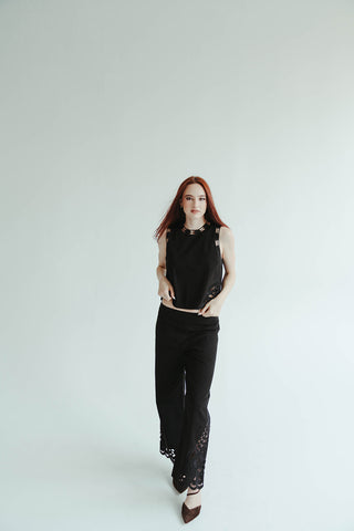 Person wearing a black sleeveless top and pants on a white background