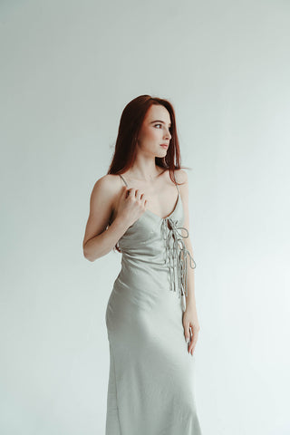Woman wearing a light green strapless dress with a belt against a white background